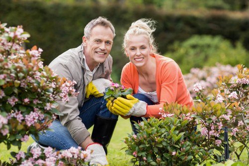 Garden maintenance team clearing overgrown shrubs in a narrow urban garden